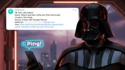 A close-up horizontal image of a Darth Vader-like character holding a mobile phone in a futuristic setting. A large notification overlay sits in the top left, displaying a message about a "New café added!" named "Wakuli specialty coffee bar (Piet Heinstraat)" in "Den Haag." A blue "Ping!" notification bubble appears above the mobile phone.